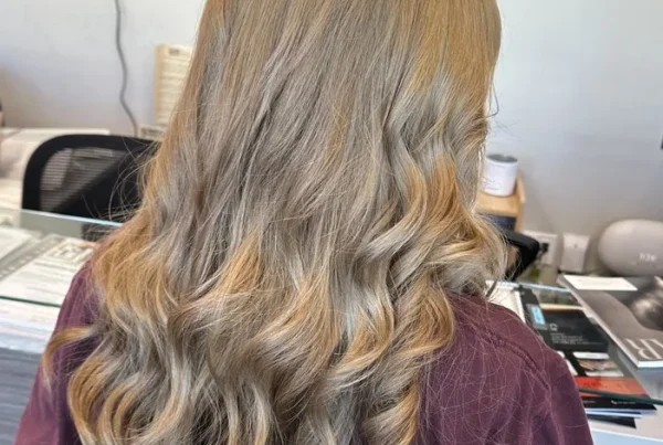 Cosmetology student showcasing a finished blonde hairstyle at RT7 Beauty College in Garden Grove