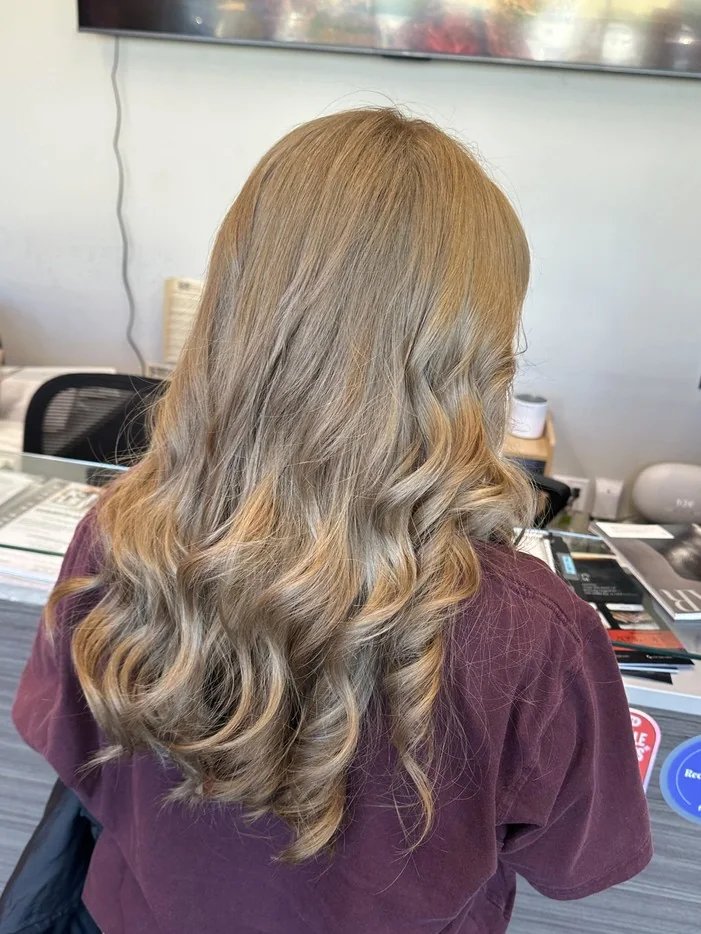 Cosmetology student showcasing a finished blonde hairstyle at RT7 Beauty College in Garden Grove