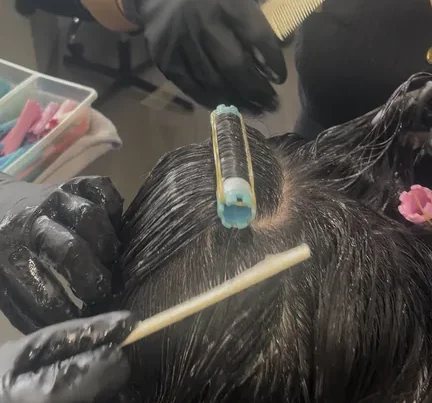 Beauty instructor demonstrating professional hair color technique to students