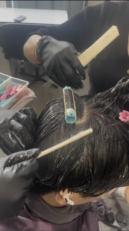 Beauty instructor demonstrating professional hair color technique to students