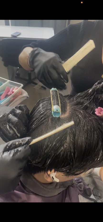 Beauty instructor demonstrating professional hair color technique to students
